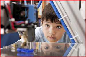 Boy watches machine intently.